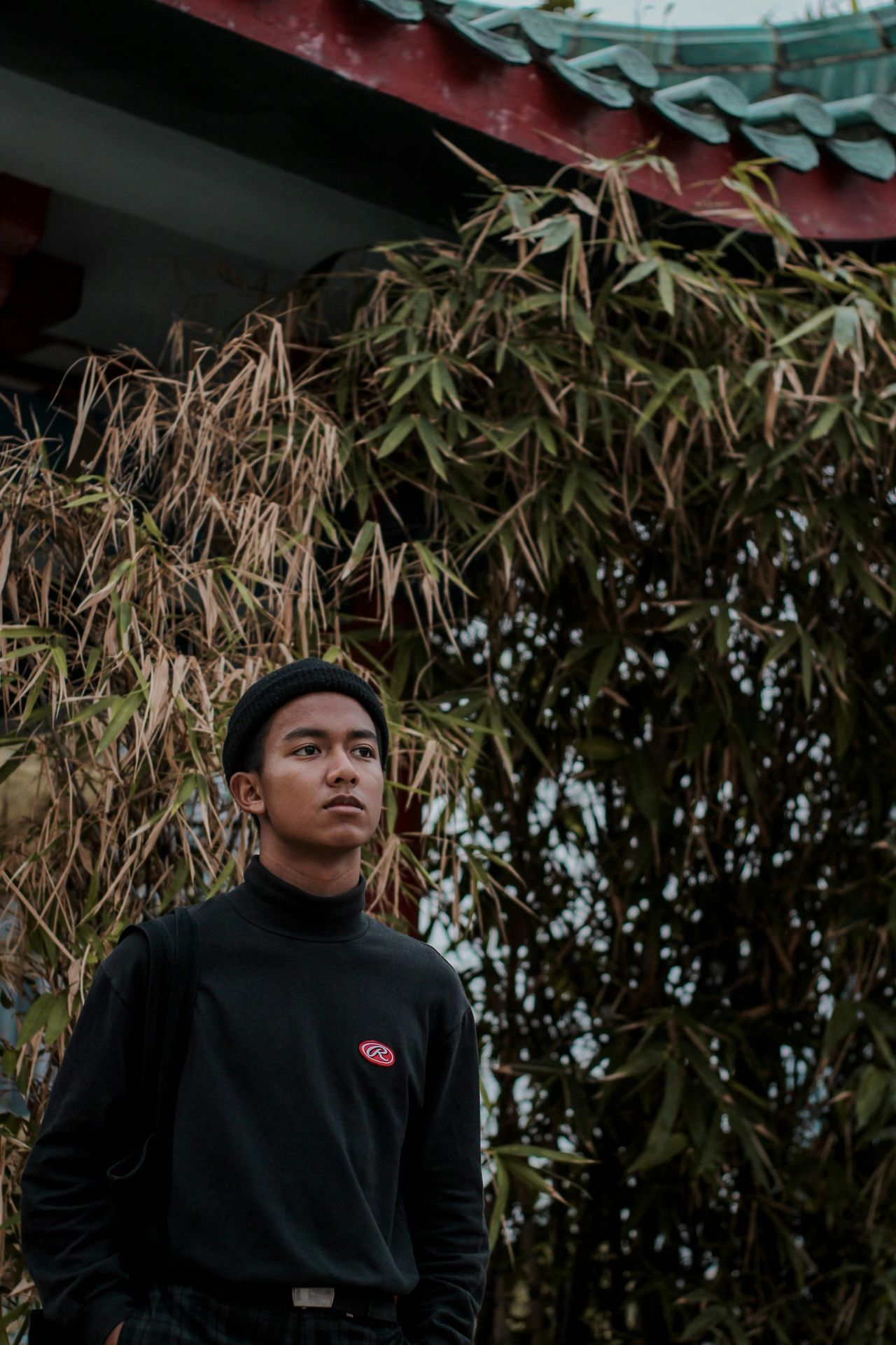 man standing near temple and bamboo trees during daytime
